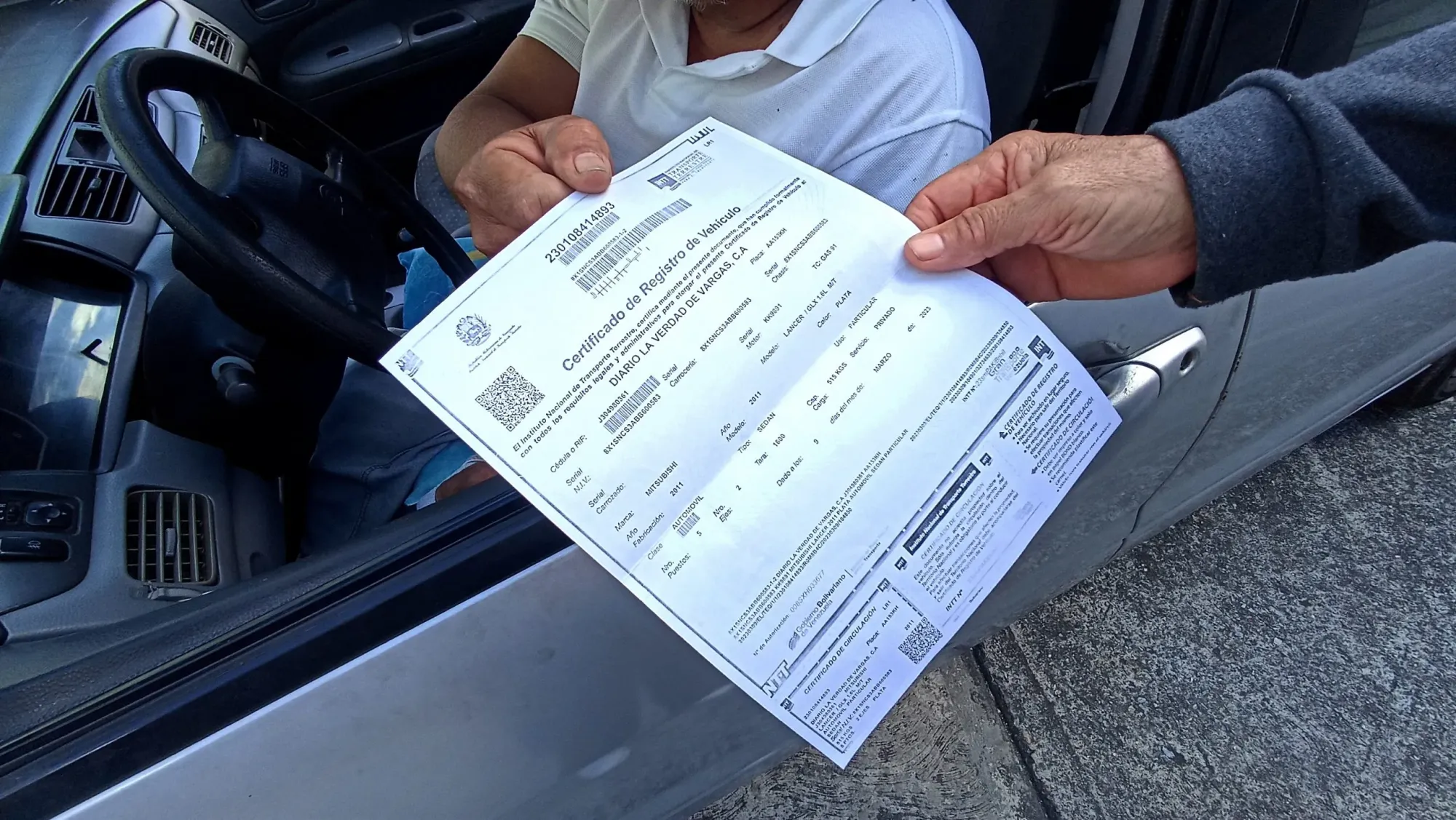 Persona entregando un certificado de registro de vehículo a otra persona dentro de un auto