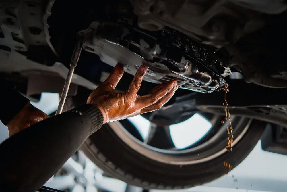 Mano sosteniendo tapa de deposito de líquido de la transmisión del auto