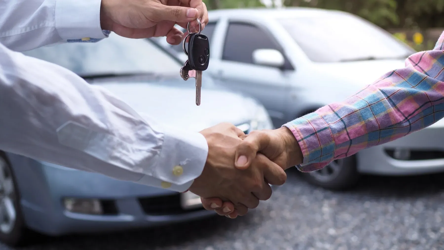 Manos estrechadas  entregando llaves de auto y de fondo autos