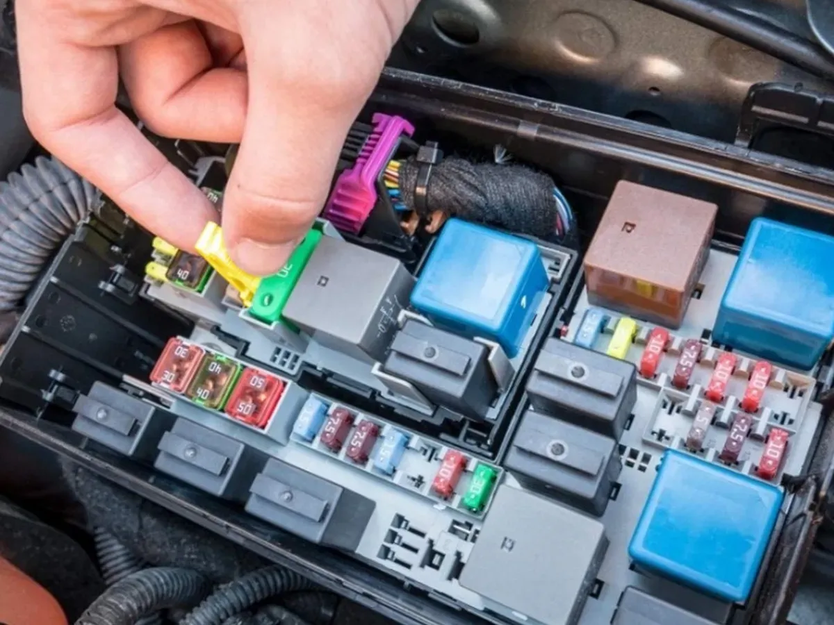 Mano colocando fusible en caja de fusibles de auto