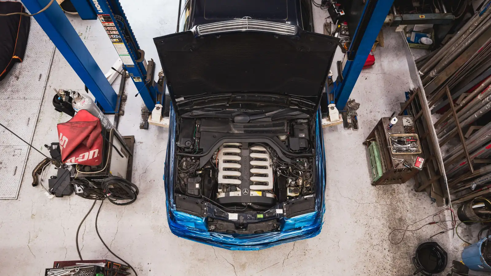 Auto azul en un taller con el capo levantado