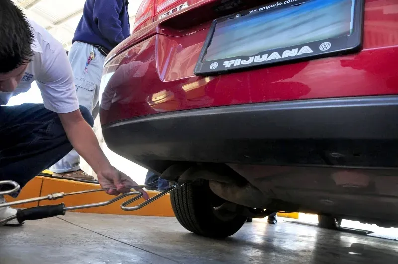 Persona insertando un analizador de CO a escape de auto para revisión 