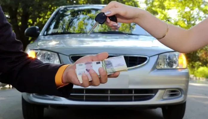 Persona entregando llaves de auto y otra entregando billetes y al fondo un automóvil 