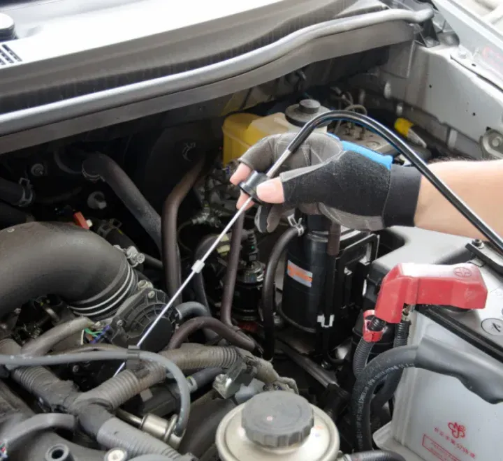 Mano sosteniendo estetoscopio automotriz sobre motor de auto