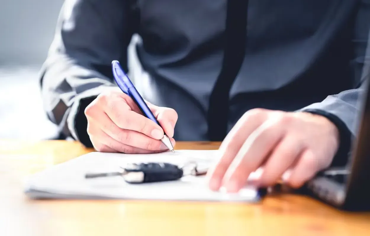 Persona firmando papel en escrito con llave de auto