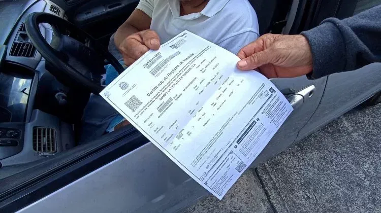 Persona recibiendo papeles dentro de un auto