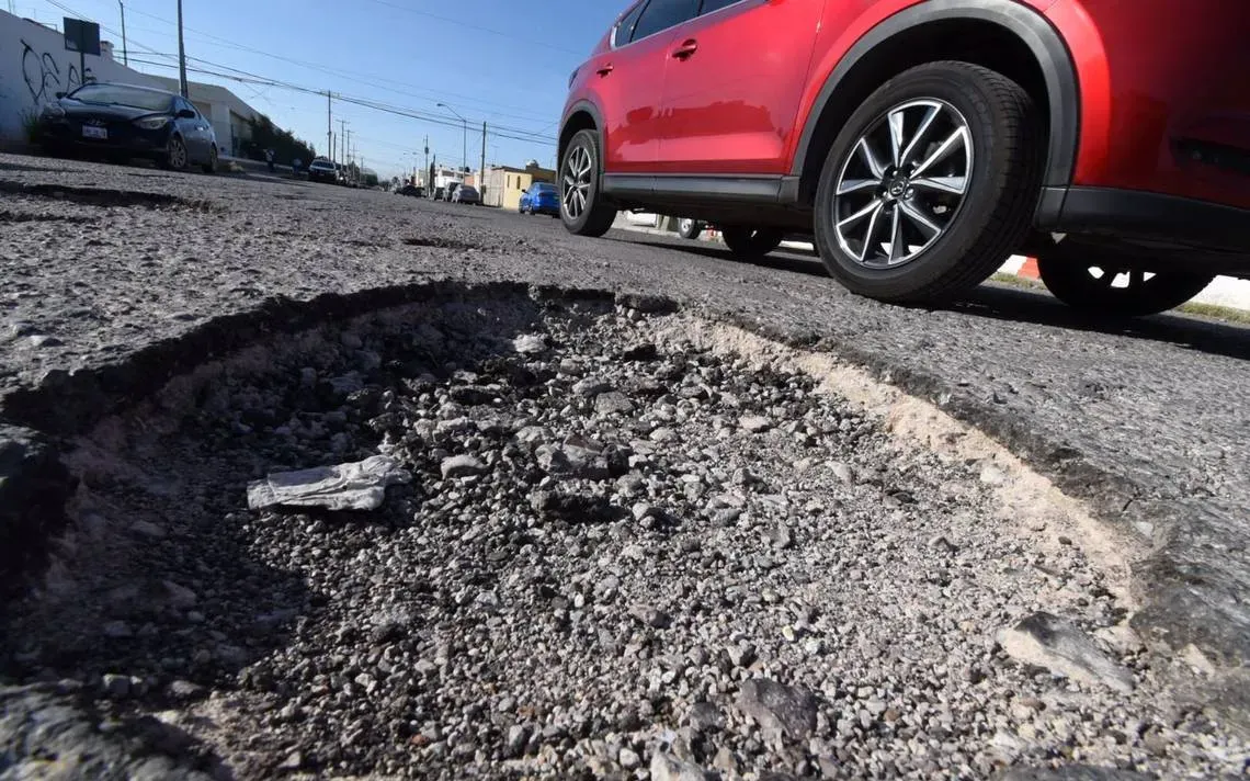 Auto pasando al lado de bache en carretera