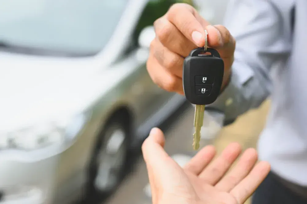 Persona haciendo entrega de llave de auto a otra