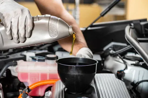 Vertiendo aceite en un embudo que pasa al motor de auto 