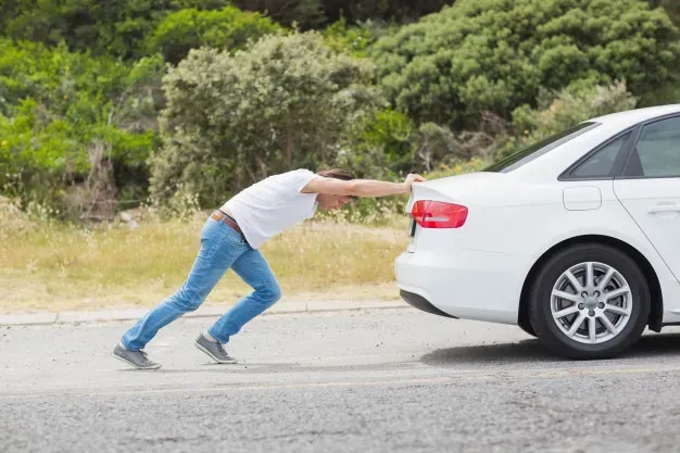 Persona empujando auto blanco  por la parte trasera