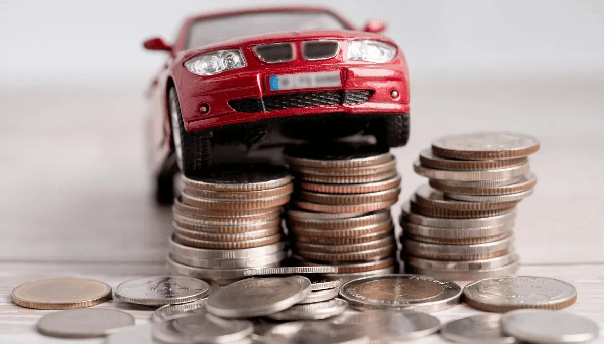 Auto rojo a escala sobre torre de monedas