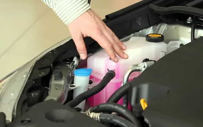 Mano sobre tanque de refrigerante en auto 