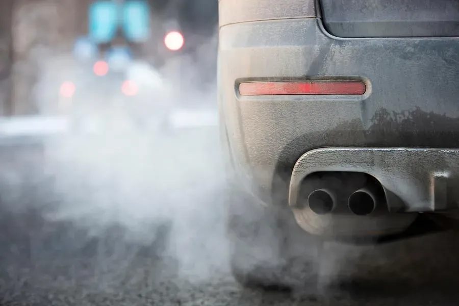 Tubo de escape de auto emitiendo humo blanco