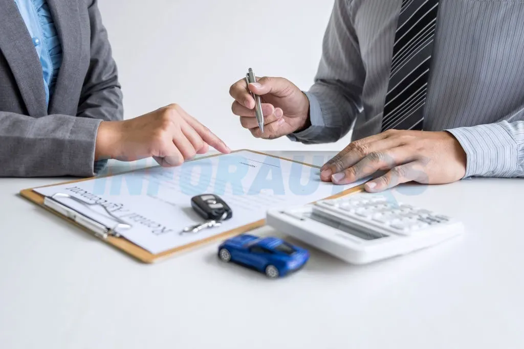 Personas revisando documentos en una mesa con auto azul a escala y llaves de auto