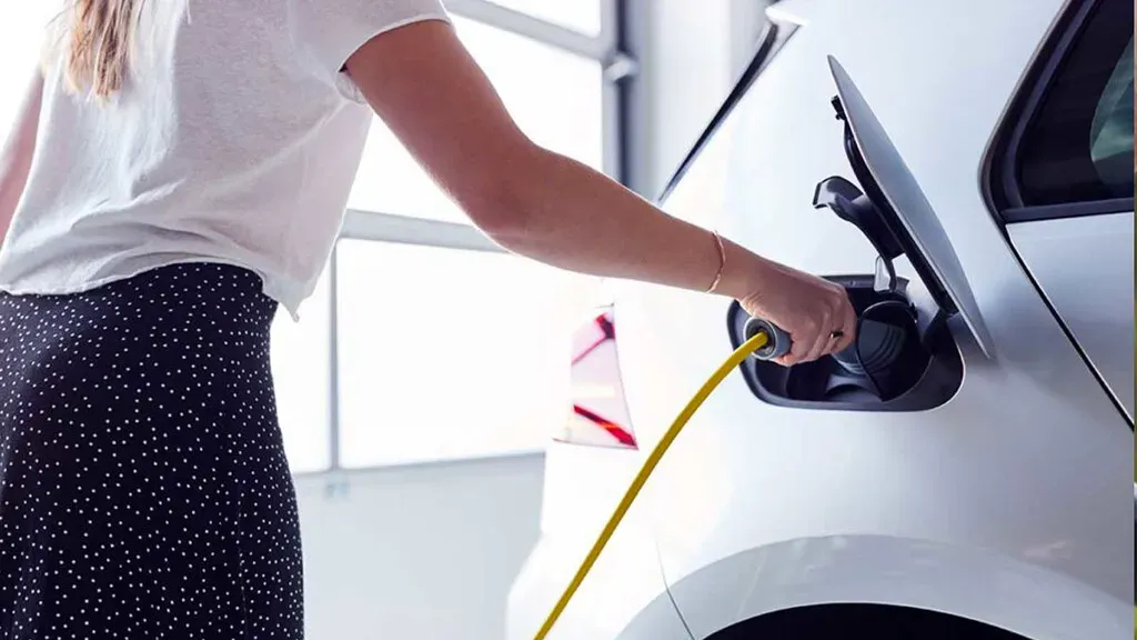 Persona cargando auto eléctrico 