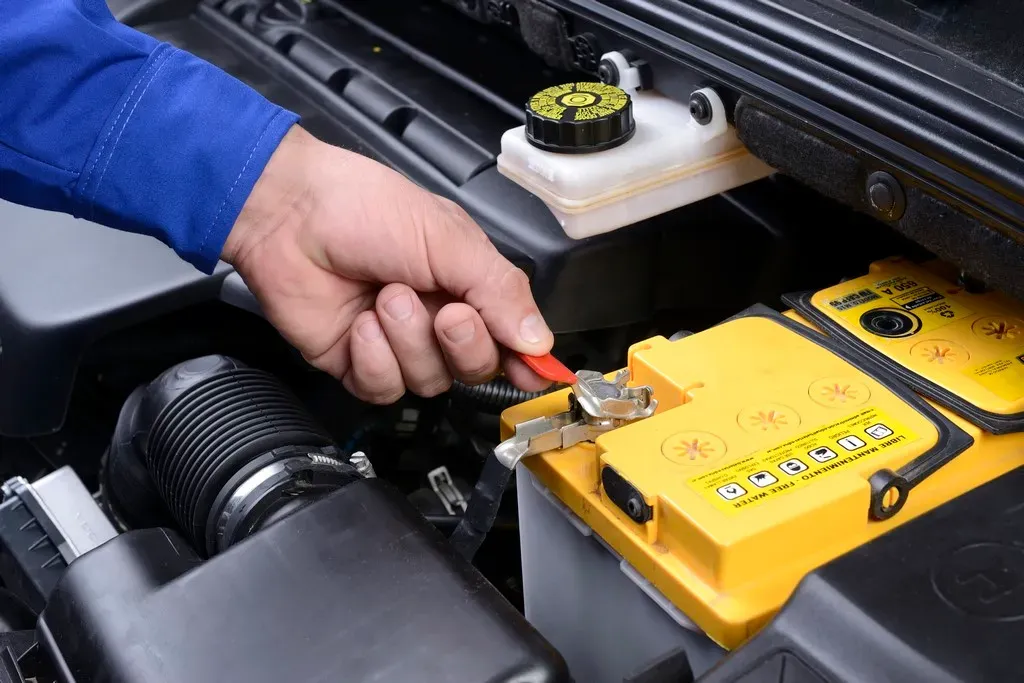 Mano desmontando batería de auto