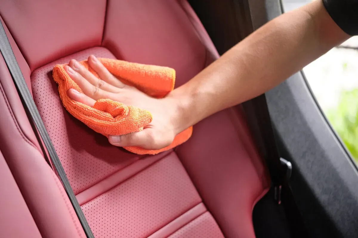 Mano frotando toalla sobre asiento de auto