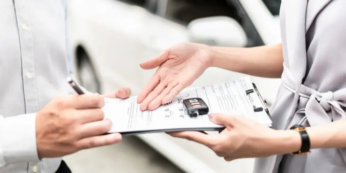 Personas firmando un documento con una llaves de auto 