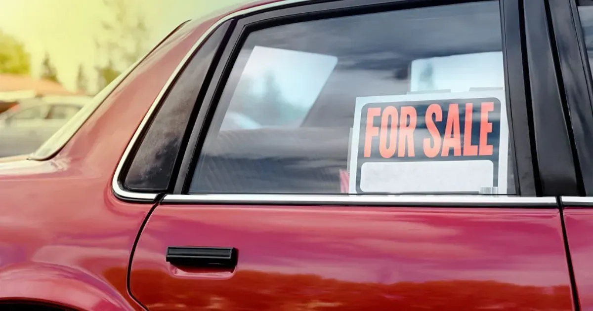 Ventana trasera de auto rojo con letrero de se vende