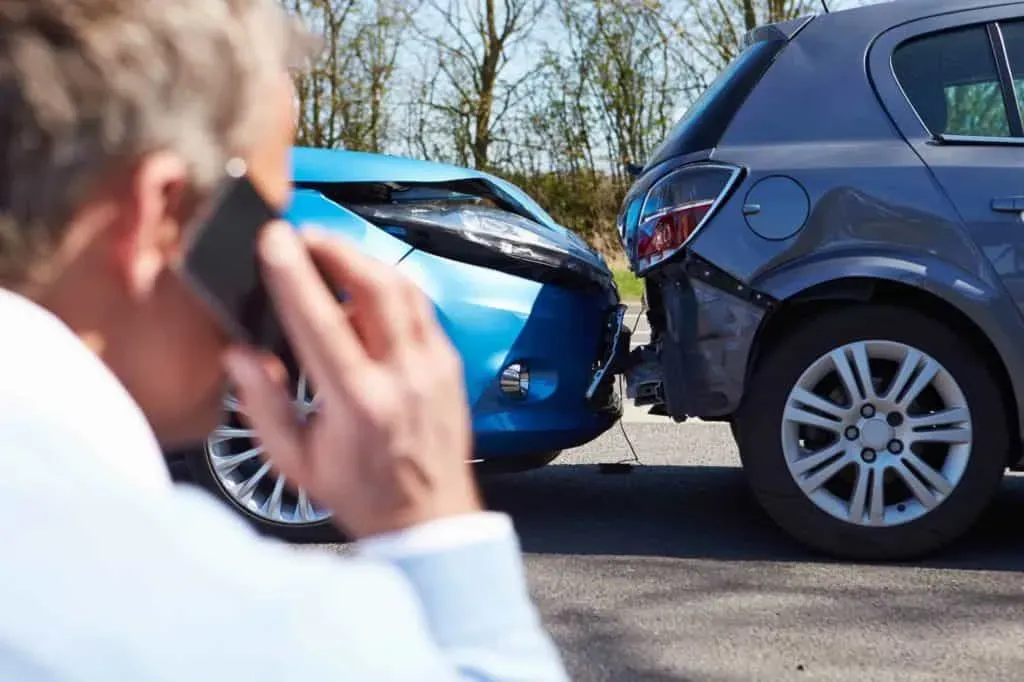 Persona usando teléfono y observando un accidente entre dos vehículos 