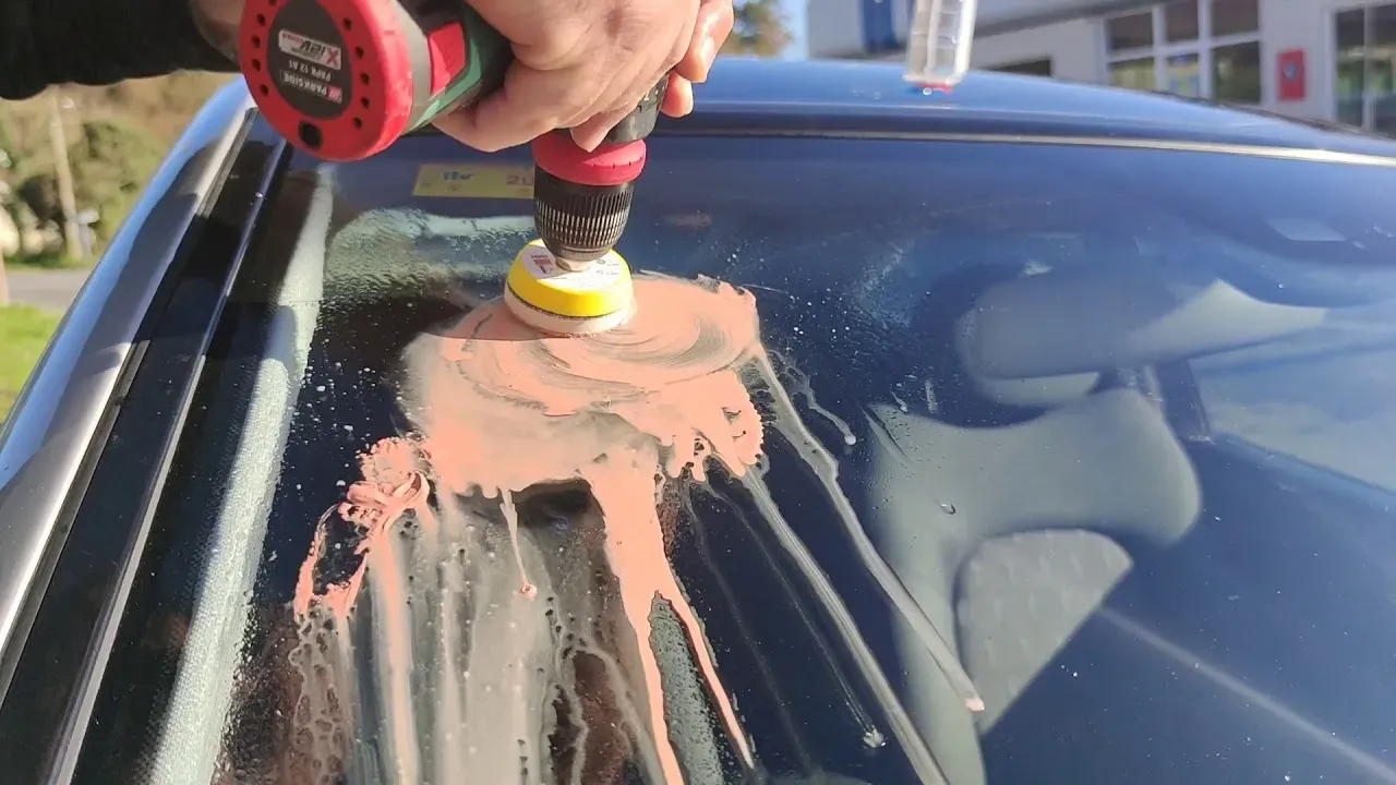 Mano frotando liquido con maquina de pulido en parabrisas  