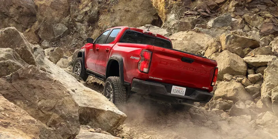 Exterior trasera del Chevy Colorado 2024 color rojo subiendo pendiente de rocas