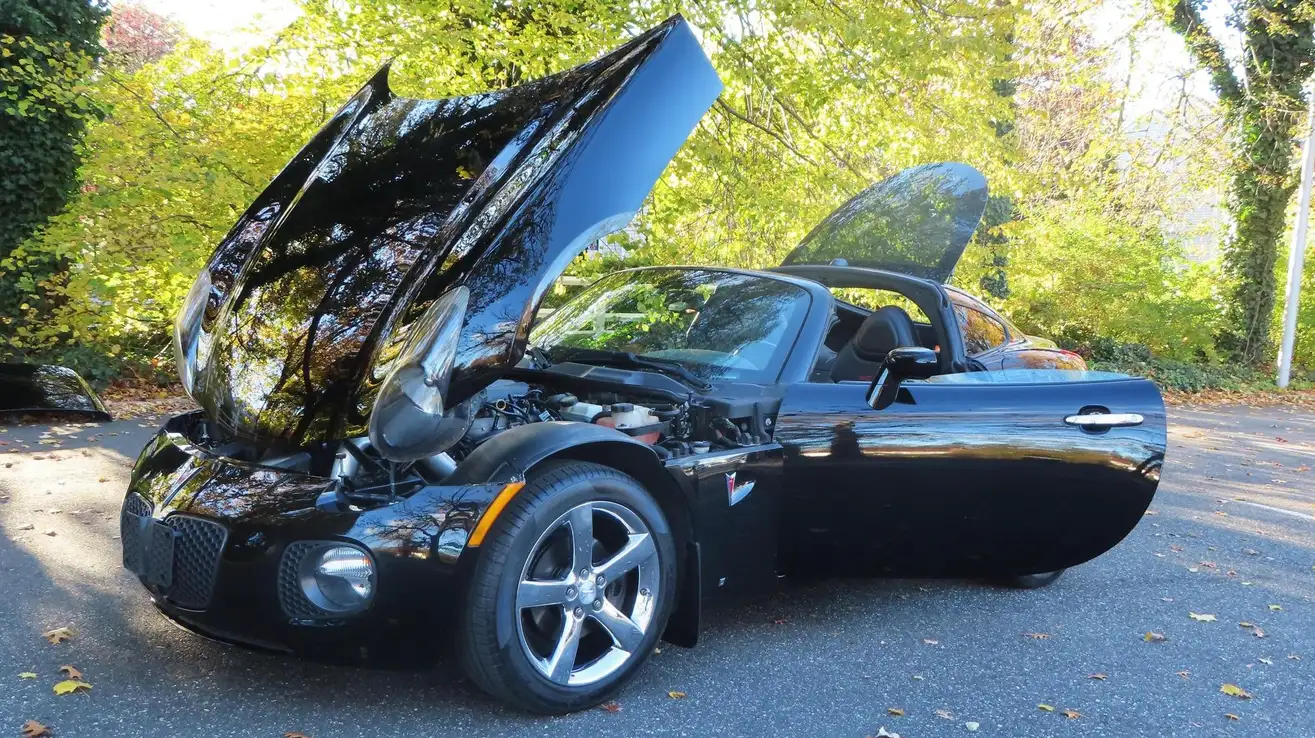 Lateral de Pontiac Solstice GXP color negro con capo, puertas y parachoques abierto  