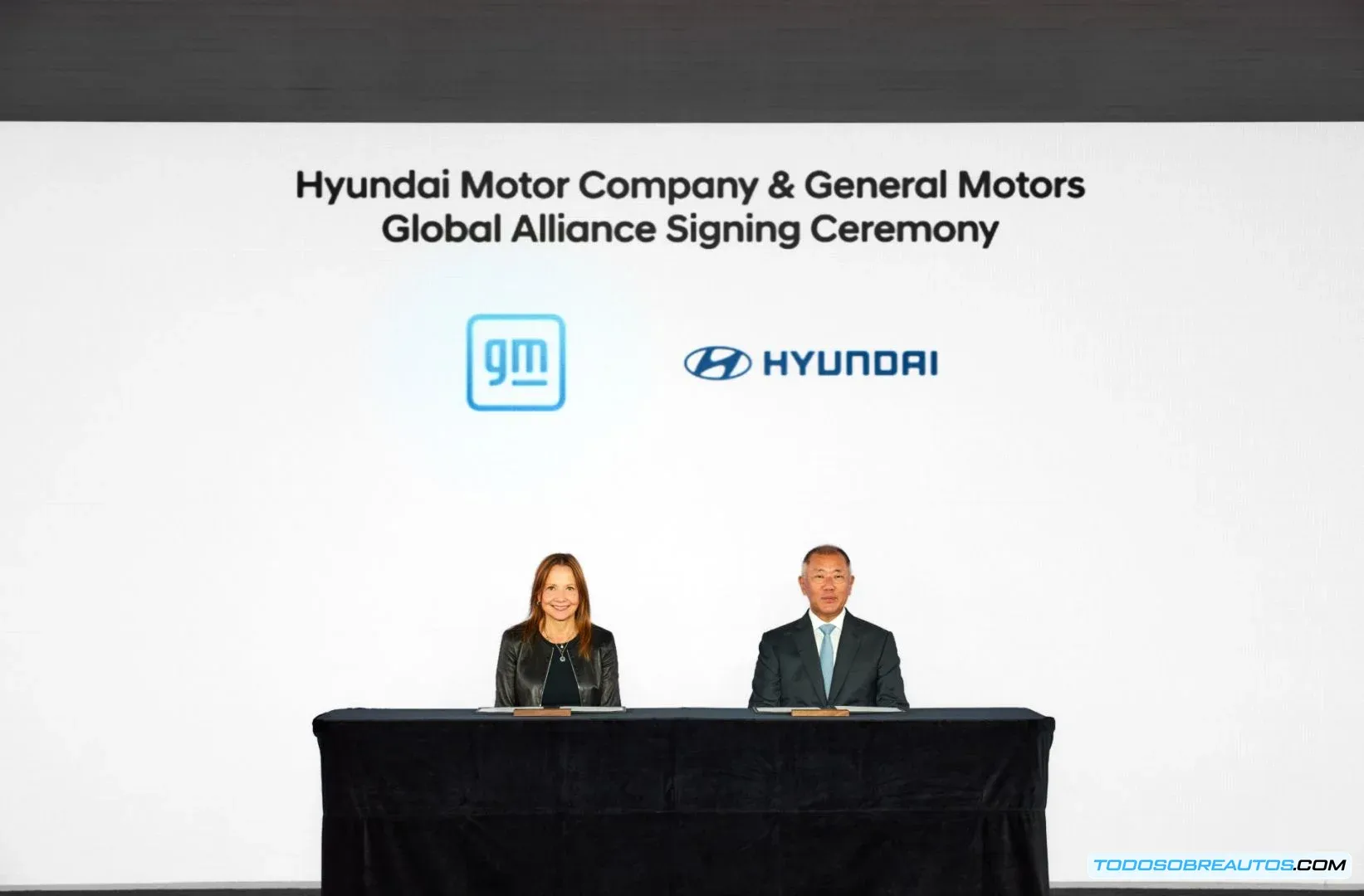 Fotografía de representantes de Hyundai y GM firmando un memorando de entendimiento, simbolizando su alianza estratégica en vehículos eléctricos, tecnologías limpias y cadena de suministro.