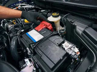 Mano encajando bien bornes de baratería en auto