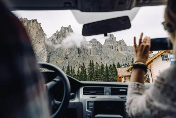 Interior de un auto con dos personas y unas vistas de montaña de fondo