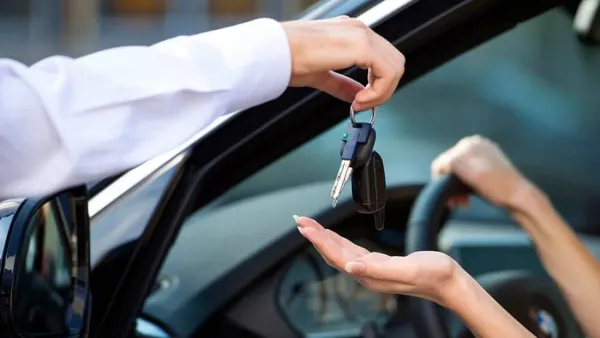 Mano sosteniendo una llave de auto y otra mano recibiéndola 