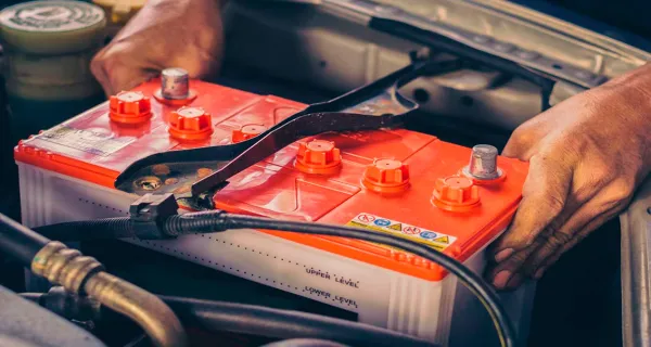 Manos colocando una bateria en un auto