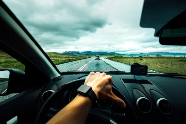 Mano sobre el volante de un auto que va por la vía