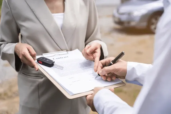 Persona firmando un contrato de compra de auto