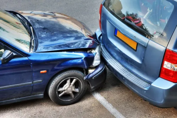 Auto azul chocando en parte delantera y otro auto azul con abolladura en parachoque trasero