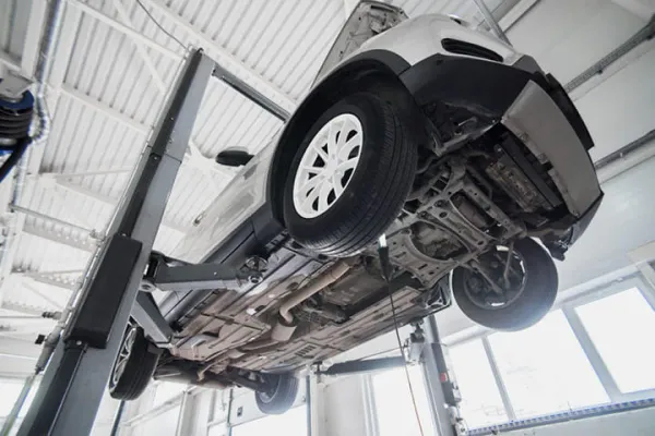 Auto blanco elevado sobre una plataforma elevadora hidráulica 