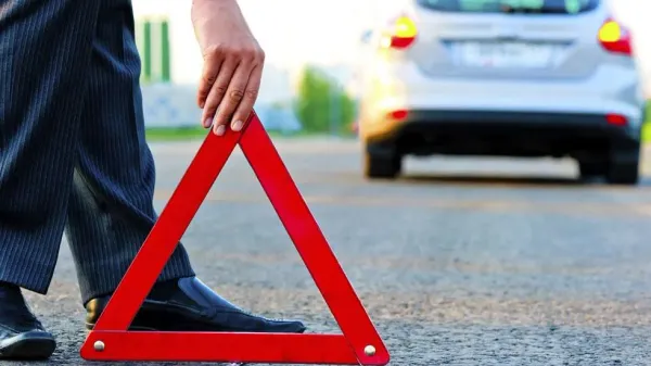 Persona colocando triangulo de emergencia en carretera