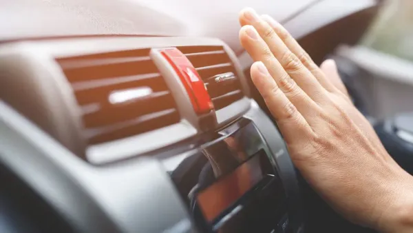 Mano frente a rejilla de aire acondicionado en un auto