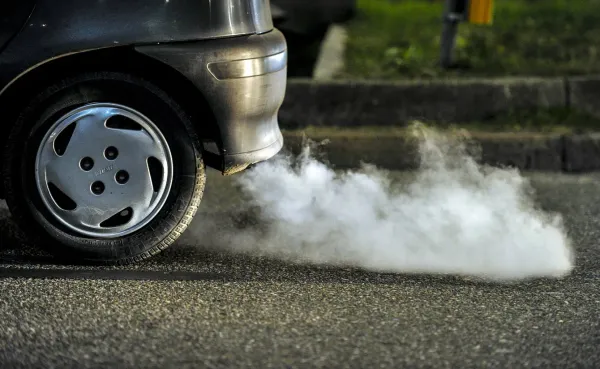 Parte trasera de auto expulsando humo blanco por escape