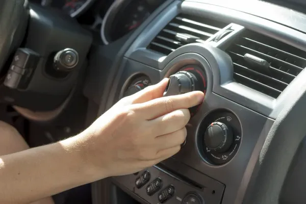 Persona girando botón de aire acondicionado en auto