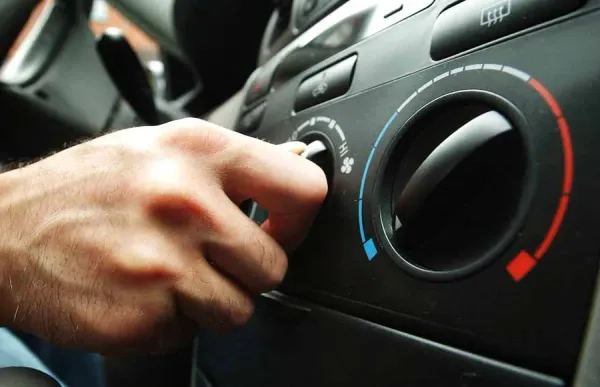 Mano girando botón de aire acondicionado de auto