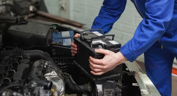 Manos colocando batería en auto