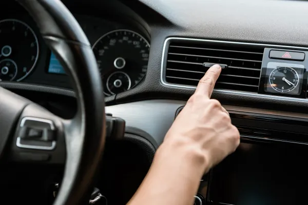 Dedo sobre rejilla de aire acondicionado en auto 