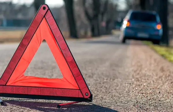 Triangulo de emergencia en carretera y auto estacionado al fondo