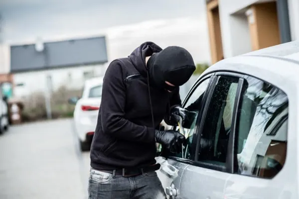 Persona con capucha forzando cerradura de auto