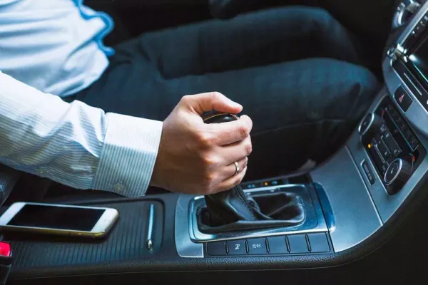 Persona en auto con mano sobre palanca de cambios