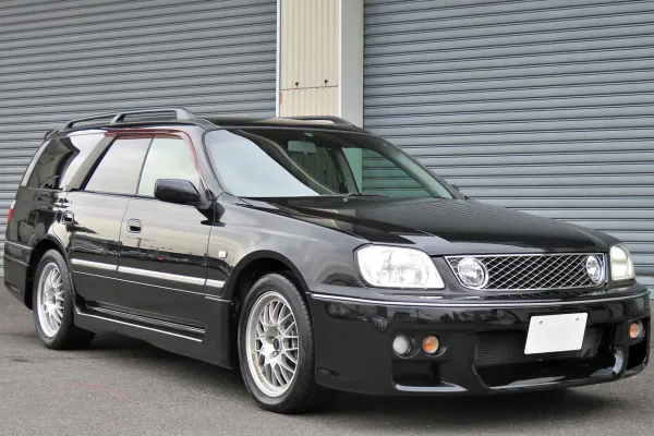 La Nissan Stagea 260RS color negro de perfil, mostrando el kit aerodinámico y los rines de aleación