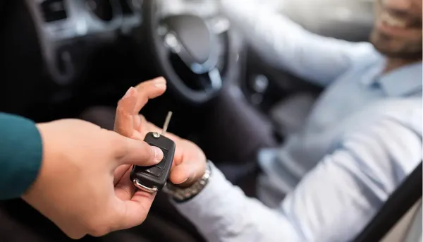 Persona dentro de auto recibiendo una llave de auto