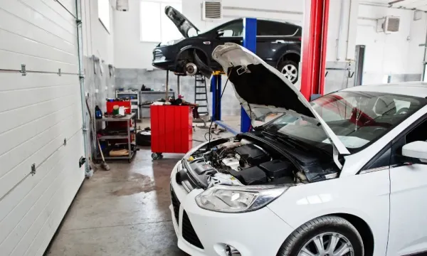 Autos en taller mecánico con capo levantado 